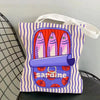 A canvas tote bag featuring a colorful print of sardines and a purple barrel design.