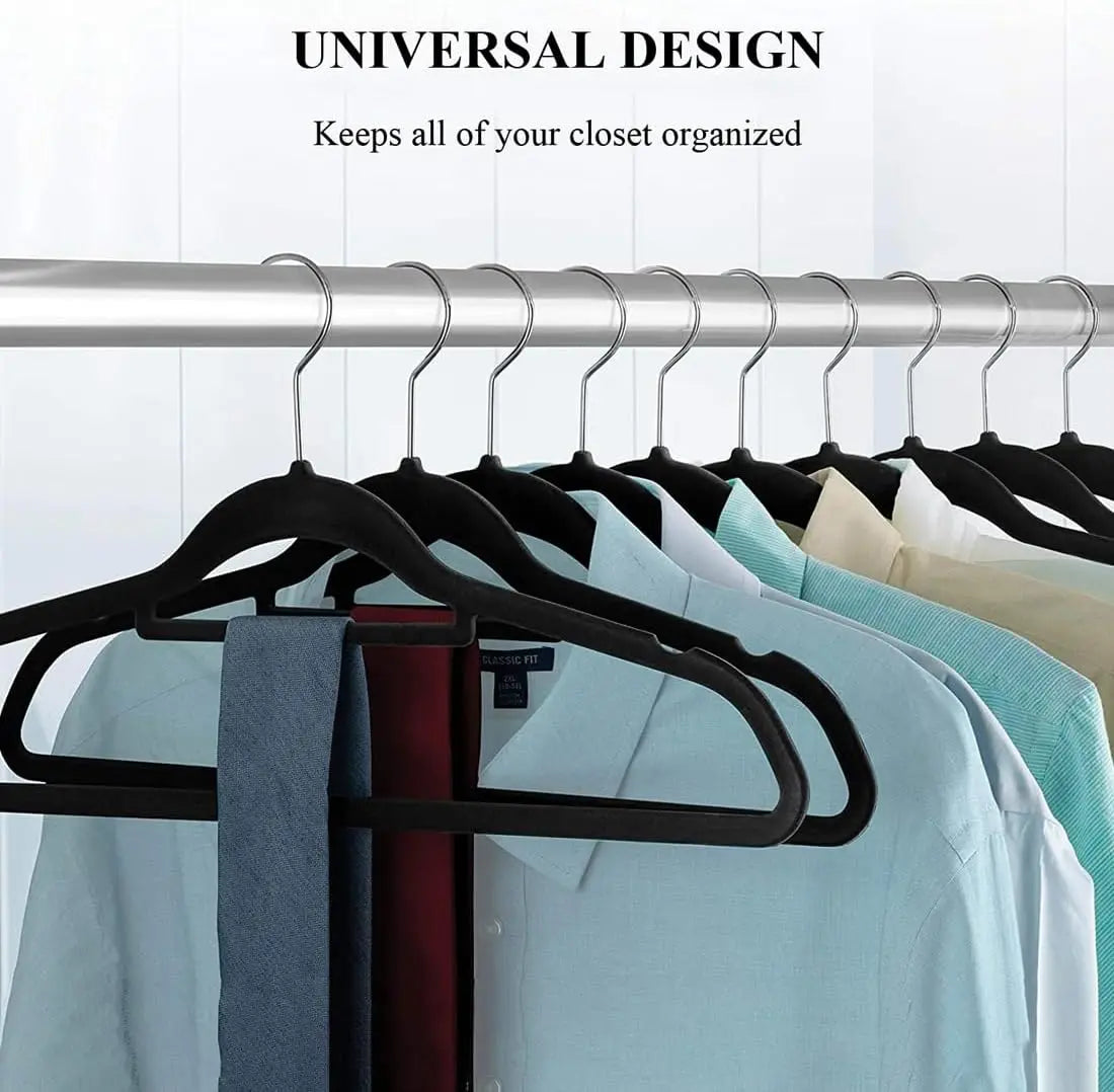 Black velvet non-slip hangers hanging clothes on a metal rod in a closet