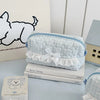 Light blue cosmetic pouch with white lace trim resting on a stack of books.