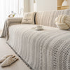 Beige und schwarz gemusterter Sofabezug mit cremefarbigem Kissen und weißer Tasse auf einem hellen Bett.