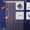A beaded string curtain with a dark blue background hangs against a deep blue wall, featuring a heart design and the word LIV