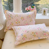 A pink floral duvet cover set with matching pillows displayed on a windowsill.