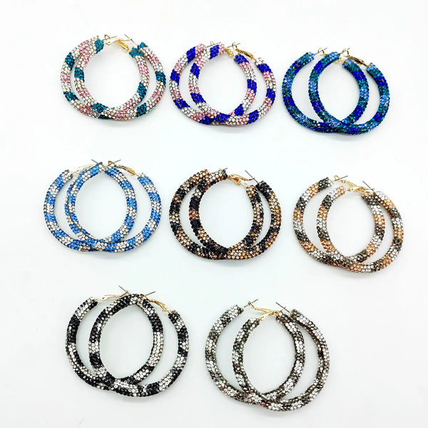 Collection d'boucles d'oreilles en forme de anneau en cristal arc-en-ciel dans différentes nuances de bleu, rose et or.