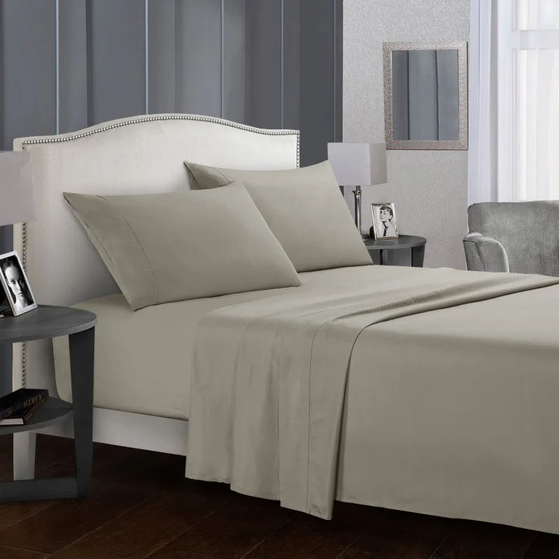 Ensemble de linge de lit en microfibre beige premium sur un lit avec tête de lit blanche et table de chevet.