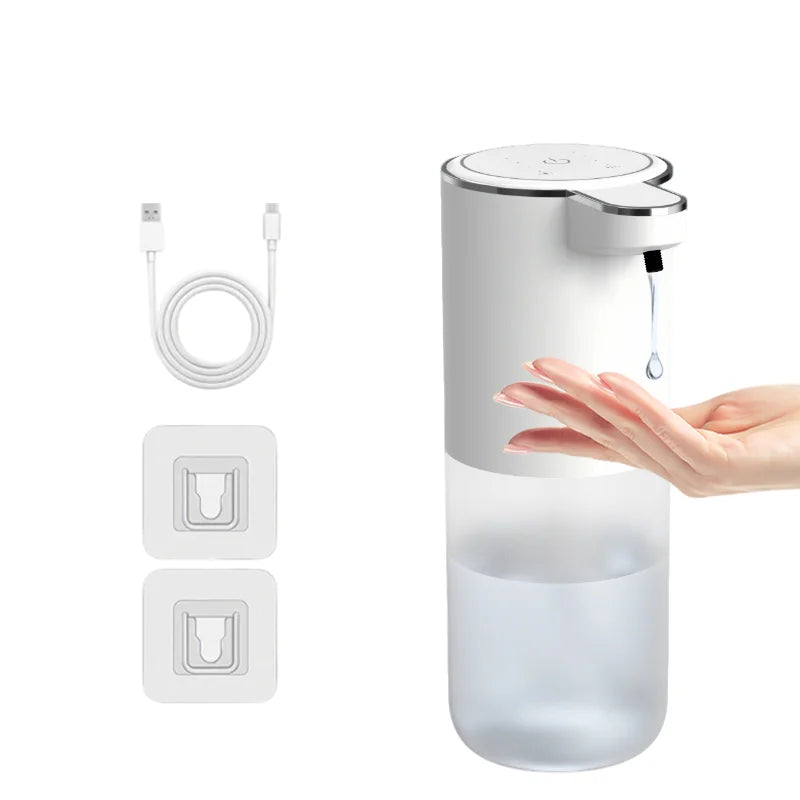 A hand is dispensing liquid from a white touchless automatic soap dispenser with a rechargeable USB charging base.