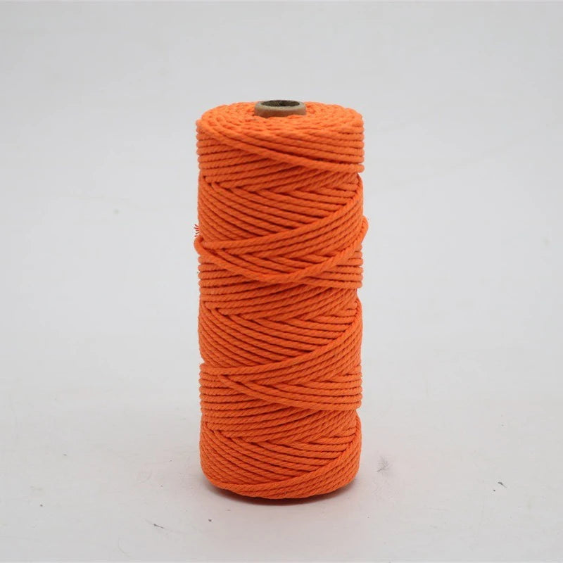 A spool of bright orange macrame cord used for crafting.