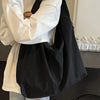 A person holds a black lightweight nylon tote bag with a secure zipper closure in front of their body.