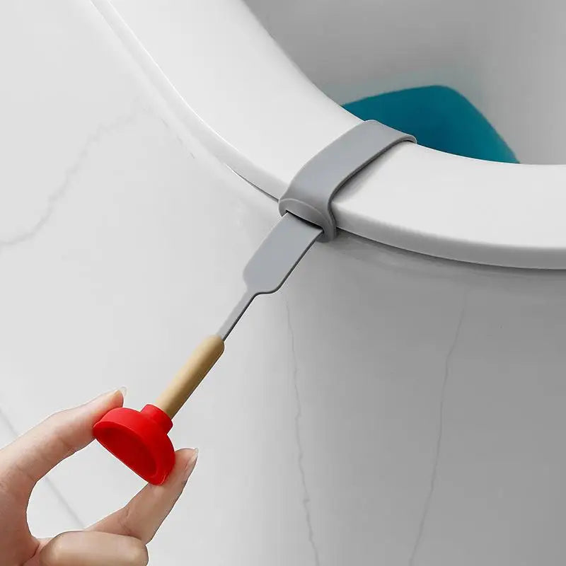 A hand is lifting a gray toilet lid lifter from the rim of a white toilet bowl.