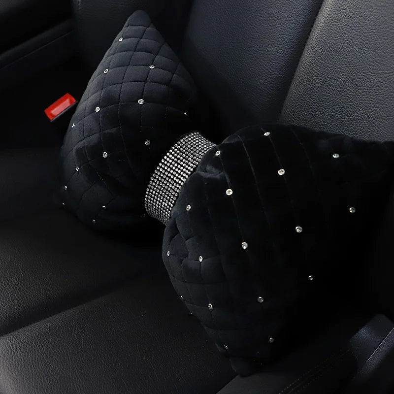Black quilted car neck pillow with a rhinestone bowknot detail resting on a black car seat.