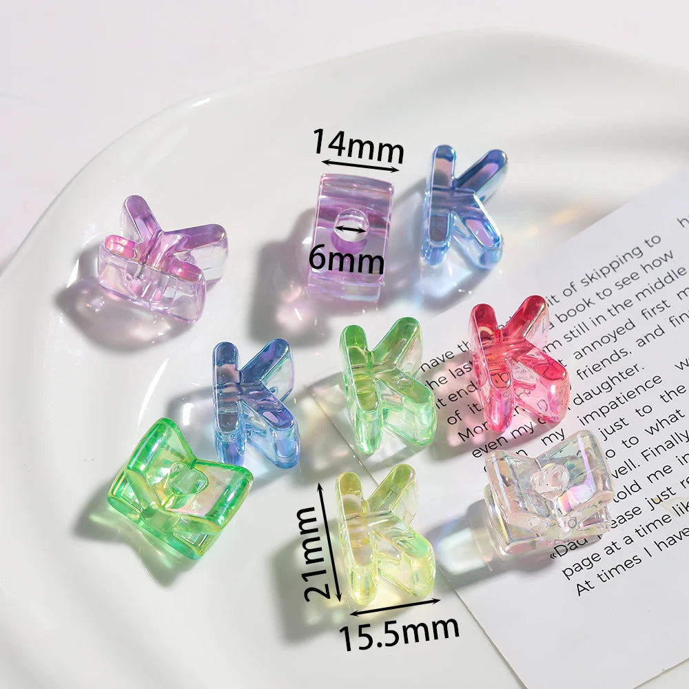 A collection of clear and colored acrylic alphabet beads for jewelry making displayed on a white plate.