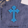 A vibrant blue embroidered cross patch on a denim fabric background.