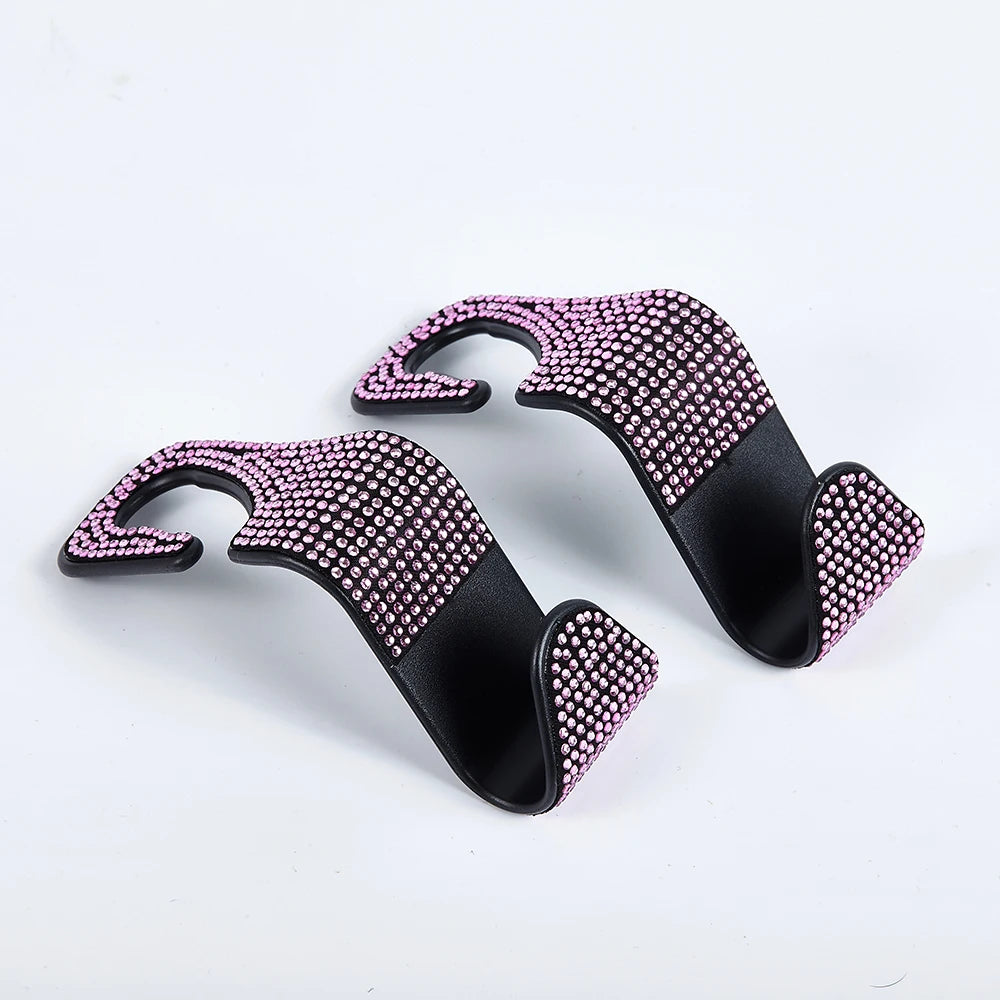 A pair of black car seat storage hooks decorated with pink crystal diamond accents.