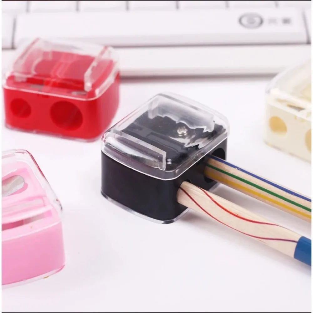 A black automatic dual-hole pencil sharpener with wooden pencils and a red plastic sharpener visible on a white surface.