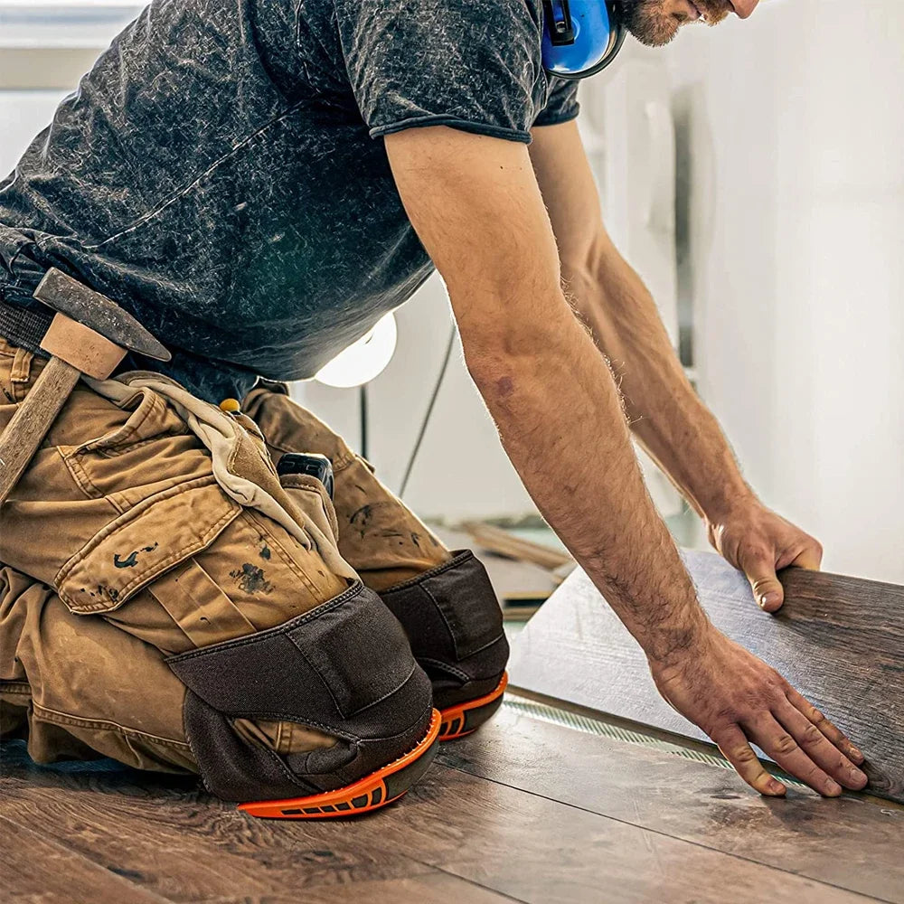 A person wearing dark clothing is using heavy-duty gel knee pads while working on a wooden surface.