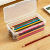 Clear plastic storage box with a lid filled with colored pencils and a single red pencil on a wooden surface.