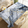 A marble tablecloth featuring blue and white veining with gold accents on a wooden table in a bright room.
