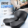 A gray ergonomic memory foam car seat cushion with lumbar support is shown in a vehicle interior context.