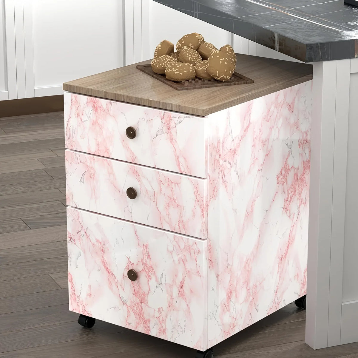 A white dresser with pink marble finish and a dark countertop displaying decorative spheres.
