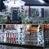 Outdoor string lights illuminating a decorated front door and porch with festive greenery.