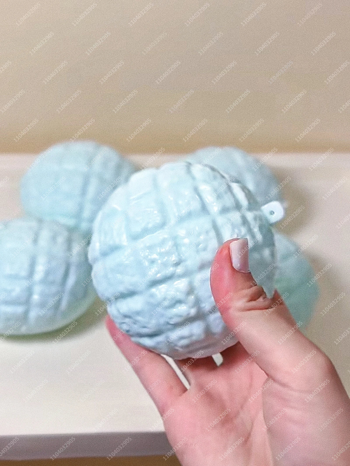 Eine Hand hält einen hellblauen, strukturierten Kartoffel-Stressball-Fidget-Spielzeug vor einem weißen Hintergrund.
