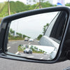 A close-up view of a black 360° wide angle blind spot mirror mounted on a vehicle.