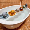 A collection of silicone animal finger puppets in various colors floating in a white bath bowl.