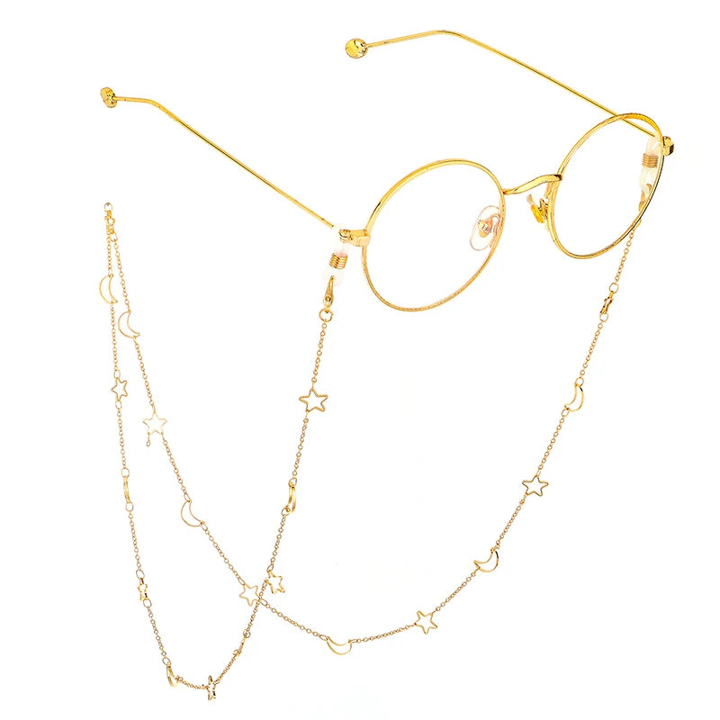 Gold-toned eyeglasses with thin metal arms and a delicate chain featuring star and moon pendants