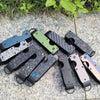 A collection of minimalist aluminum key organizers in various black, green, and silver finishes resting on a light stone surf
