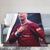 Ein Fußballspieler in einem roten Trikot ist auf einer Decke auf einem Sofa zu sehen.