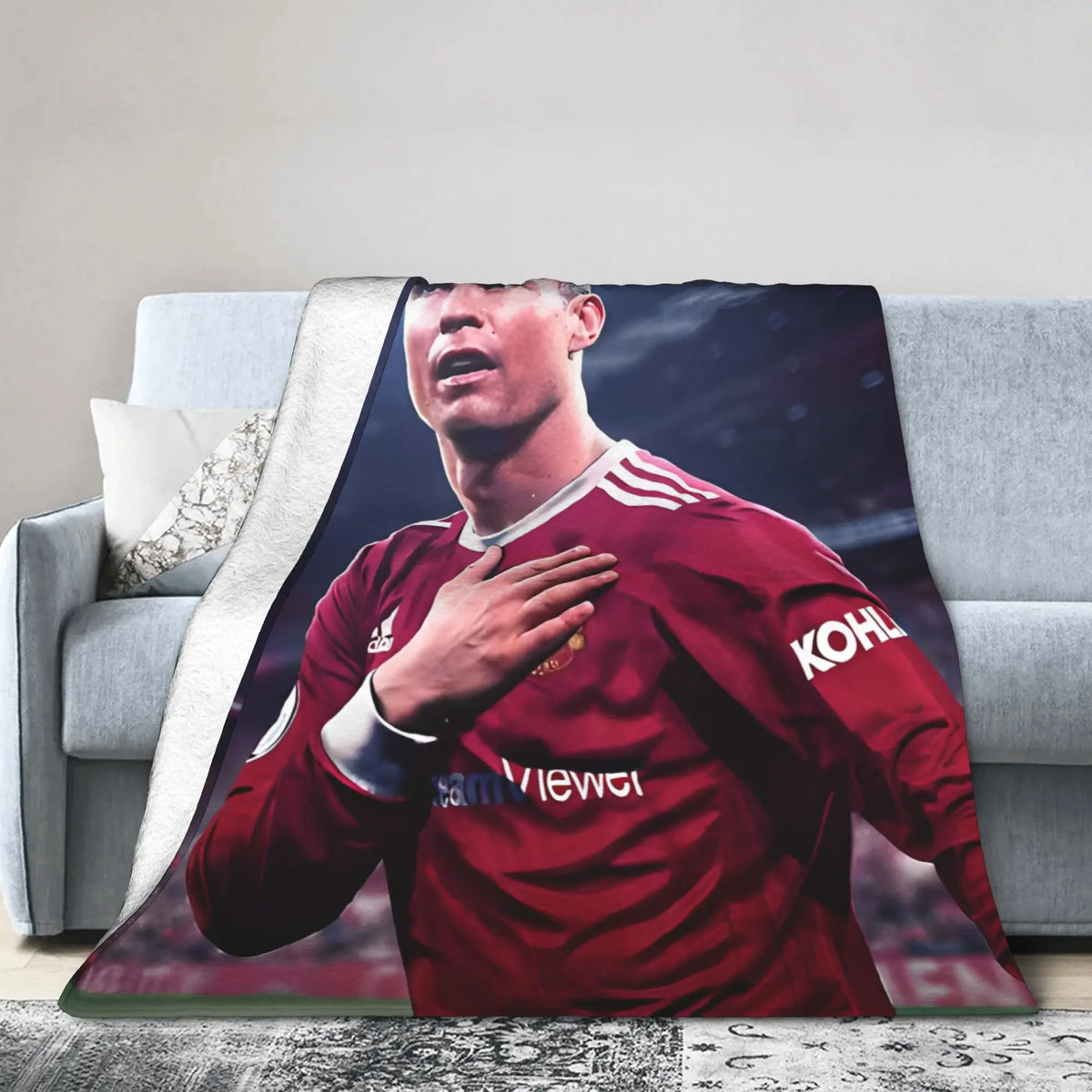 Ein Fußballspieler in einem roten Trikot ist auf einer Decke auf einem Sofa zu sehen.