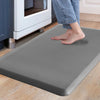 A person's feet standing on a gray anti-fatigue mat placed on a light wooden floor near an oven.