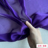 Purple sheer silk chiffon fabric being held and draped by a hand.
