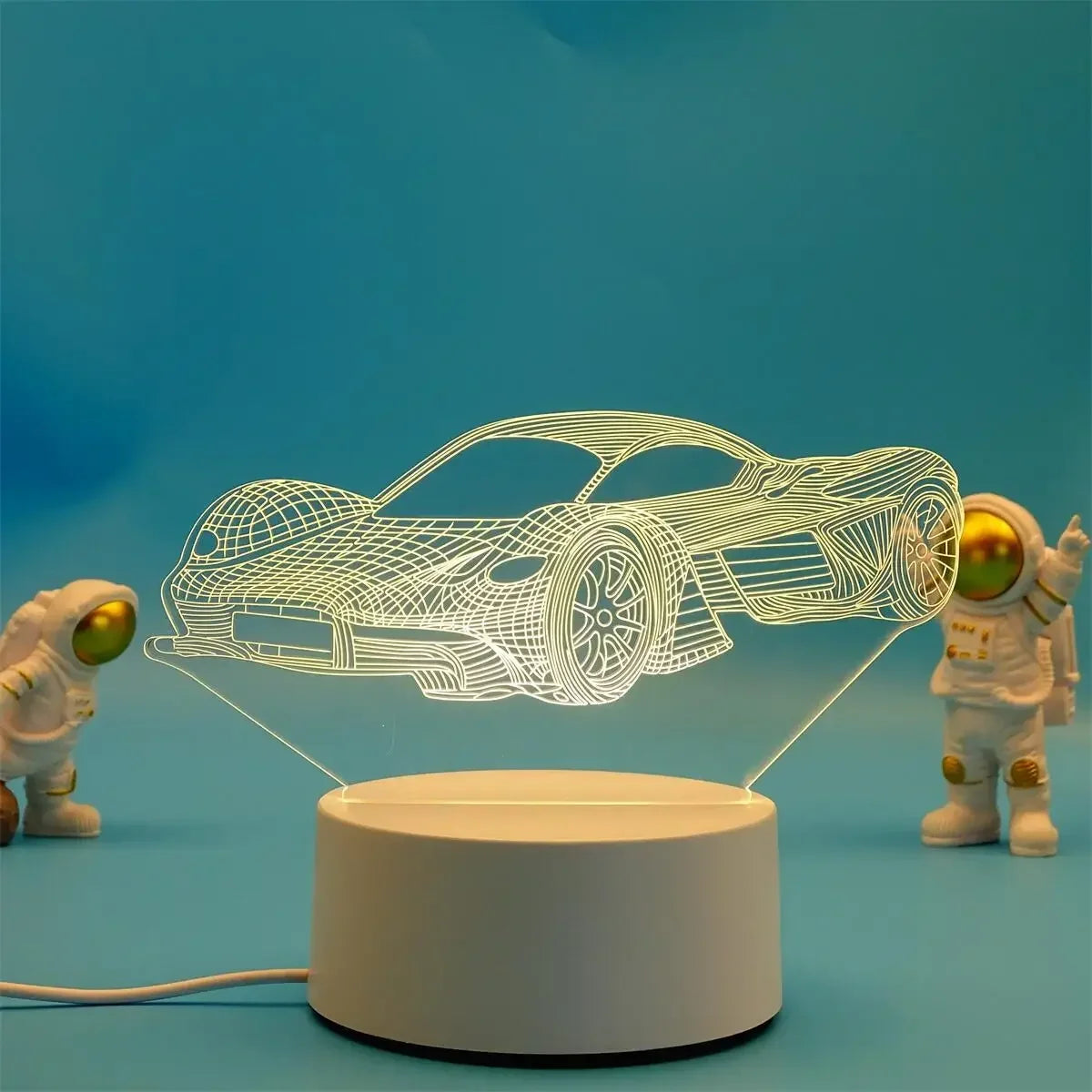 A wireframe 3D illusion light sculpture of a car floats above a white base with two small astronaut figures.