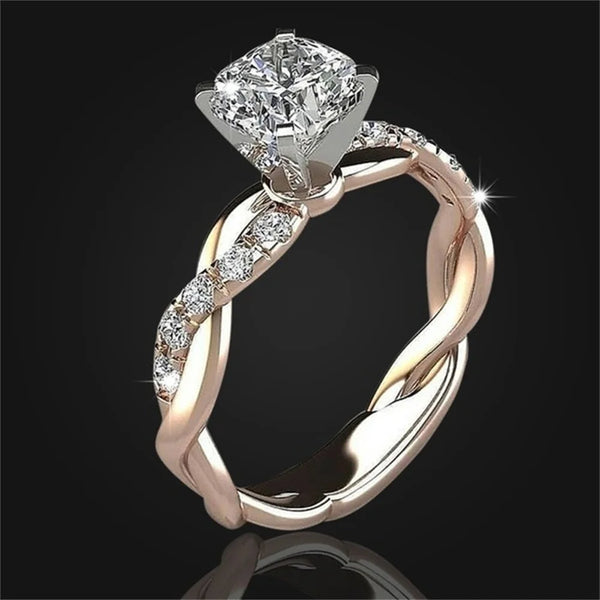 A close-up of a two-tone princess cut CZ engagement ring featuring a brilliant diamond centerpiece and pave-set stones on the