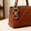 A brown quilted leather handbag with gold hardware is shown on a light surface.