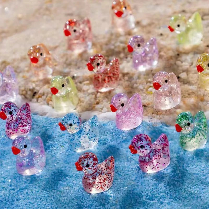 A collection of ten glitter resin duck figurines in various colors scattered on a blue surface.