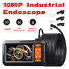 A black industrial endoscope camera with a coiled cable and various inspection tools is shown.