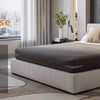 A set of four brown adjustable bed sheet corner holders is shown next to a modern bed and bedding.