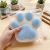 A hand holds a soft, light blue silicone cat paw squeeze toy for stress relief.