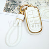 A white TPU car key fob cover with a gold chain attached to a white cord.