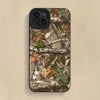 A silicone phone case featuring a forest camouflage pattern of tree branches, leaves, and moss.