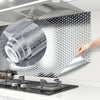 A hand is applying self-adhesive aluminum foil to a kitchen backsplash surface.