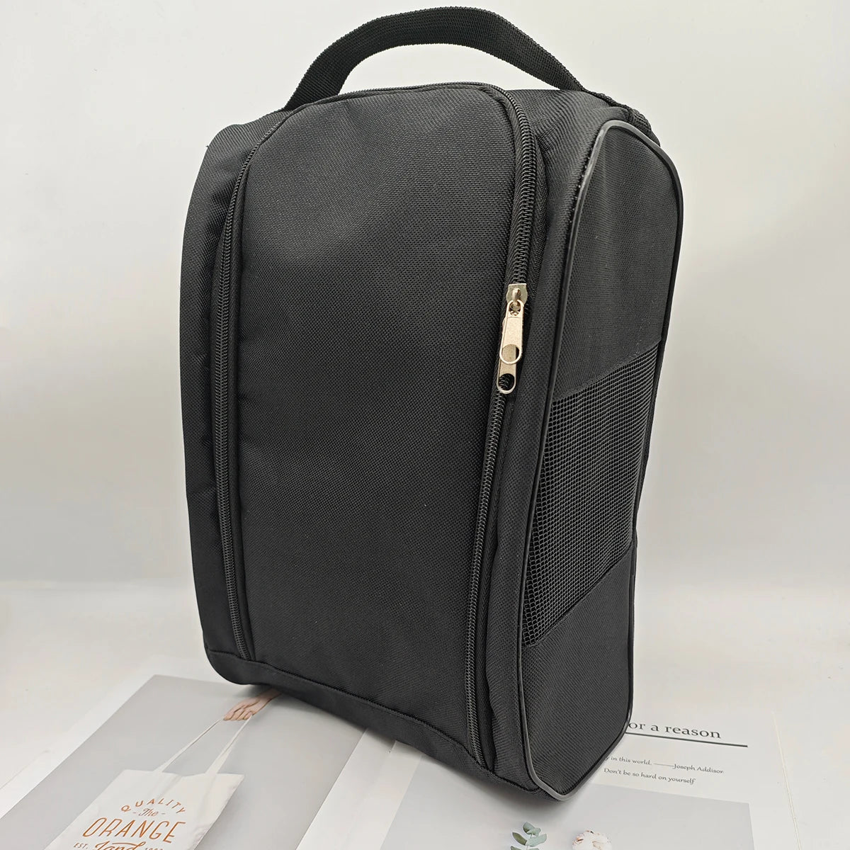 A black breathable oxford cloth shoe storage bag with a top handle and zipper.
