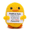 A yellow crochet duck doll with black eyes and an orange beak, holding a card that says You're Awesome!