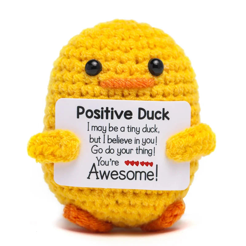 A yellow crochet duck doll with black eyes and an orange beak, holding a card that says You're Awesome!