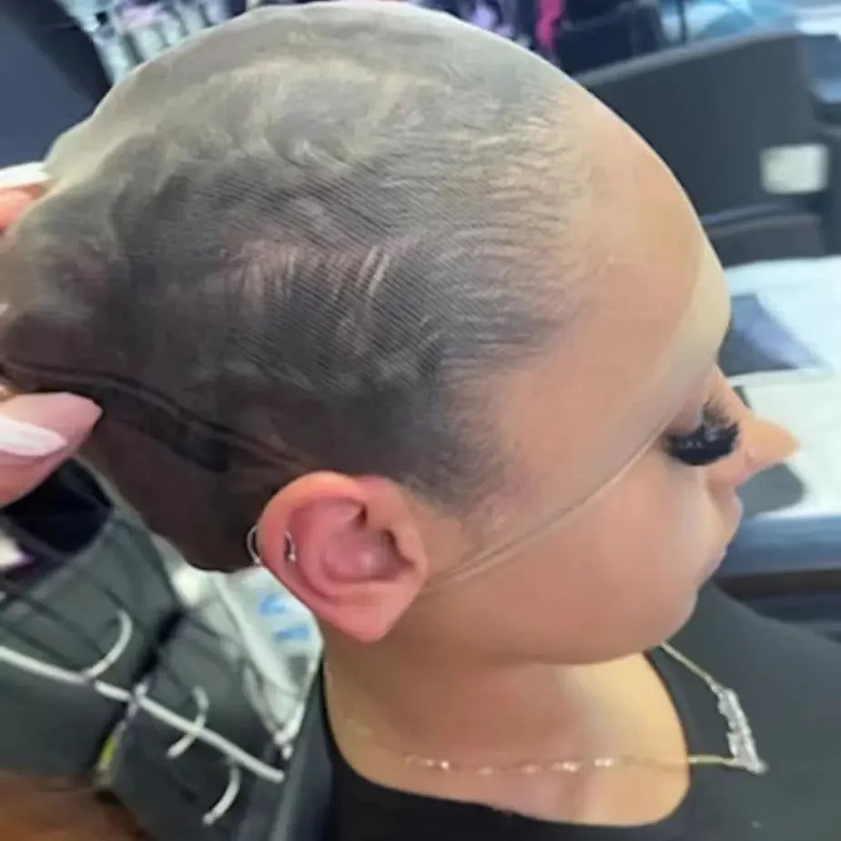 A close-up of a person's head showing an invisible lace wig cap being applied or worn.