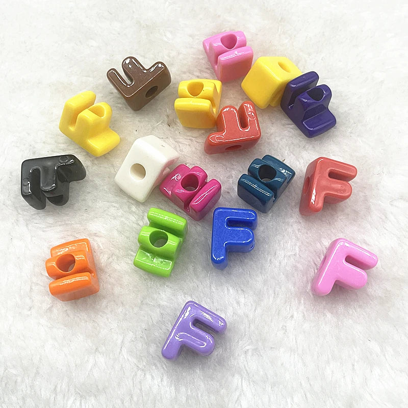 A collection of ten mixed colored alphabet letter beads scattered on a white, fluffy surface.
