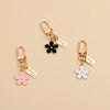 Gold-toned silicone key fob cover with a black flower charm and a pink flower charm