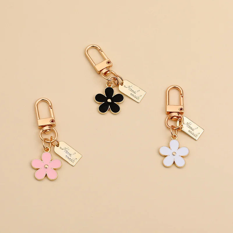 Gold-toned silicone key fob cover with a black flower charm and a pink flower charm