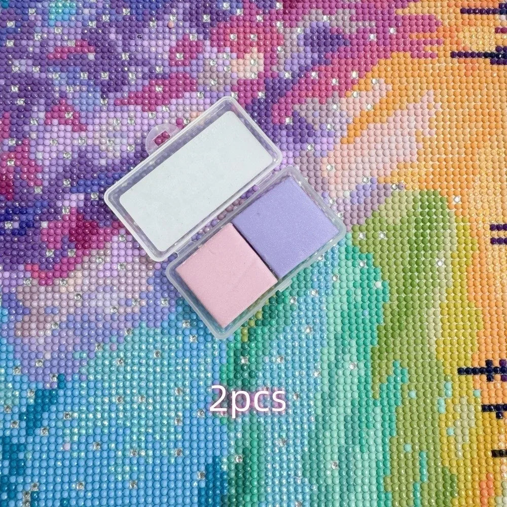 Two silicone diamond painting clays in pink and purple are displayed in a clear plastic container on a colorful textured back